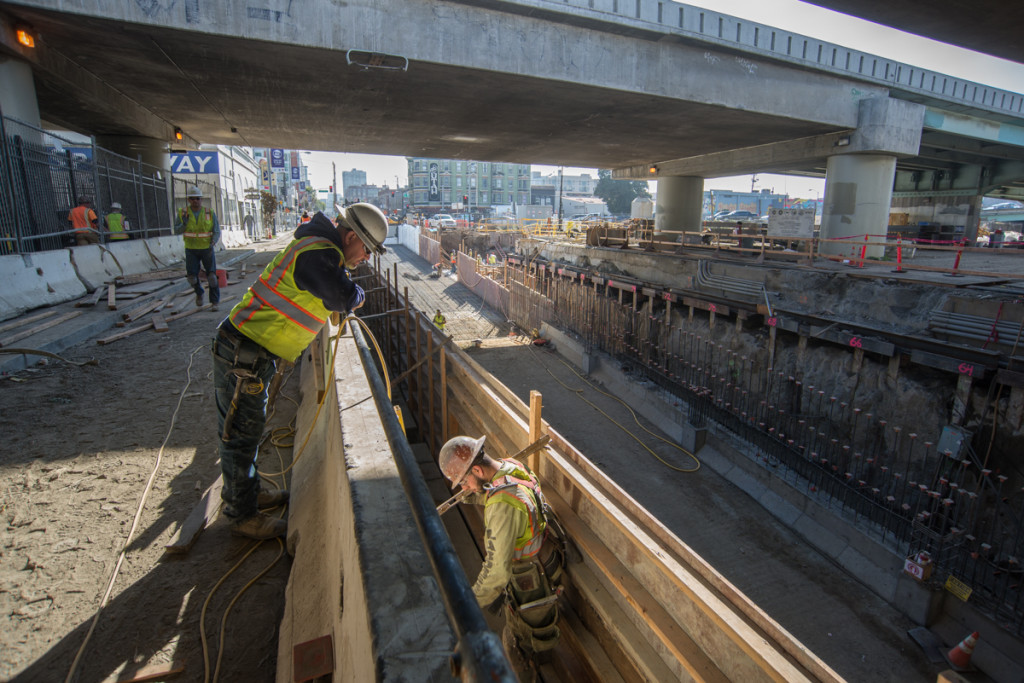 Workers install waterproofing and build temporary wooden forms before pouring concrete for the new interior walls of the tunnel portal.