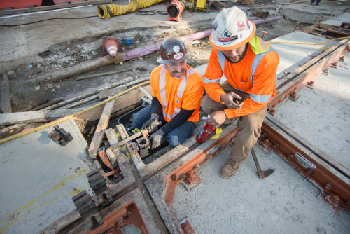 Workers prepare to weld grounding copper to the tracks, using a rapidly-burning powder which burns at a high temperature.